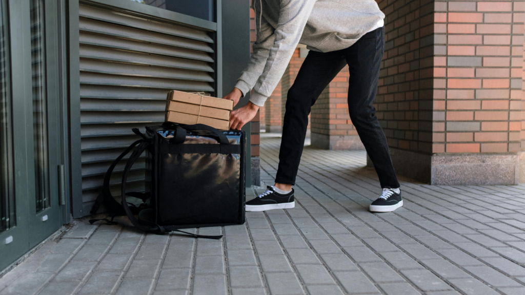 A man packing a food delivery bag with multiple food boxes.