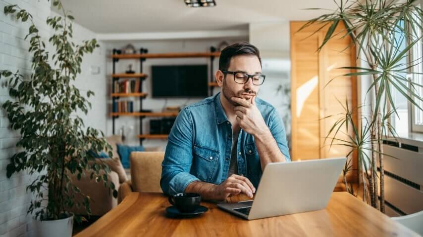 A man looking and a laptop screen and thinking.