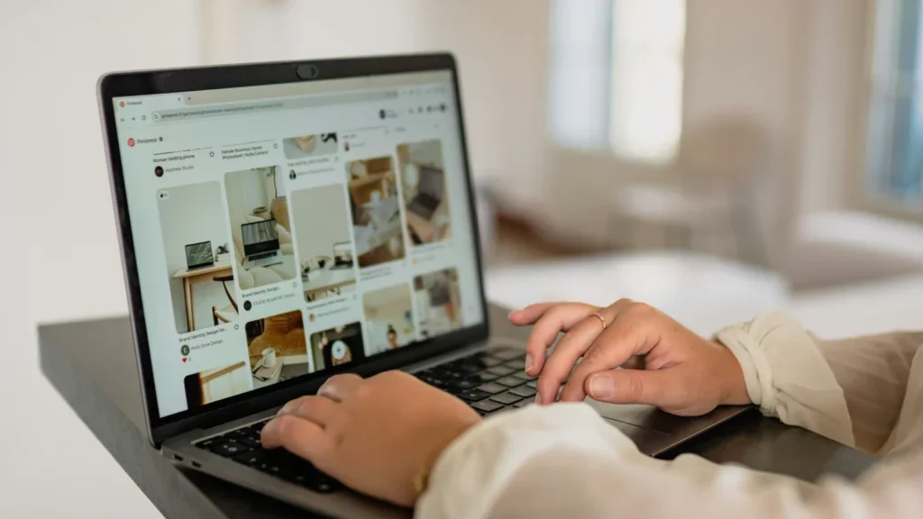 A woman using a laptop to scroll through Pinterest pins.