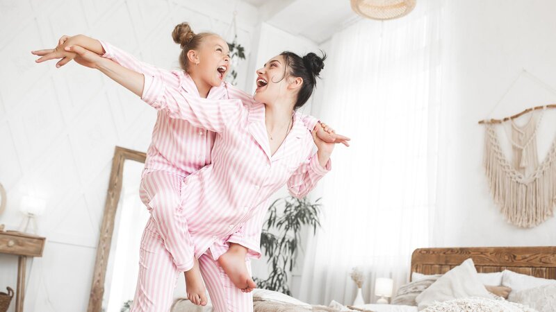 A mom is holding a daughter with their pajamas on