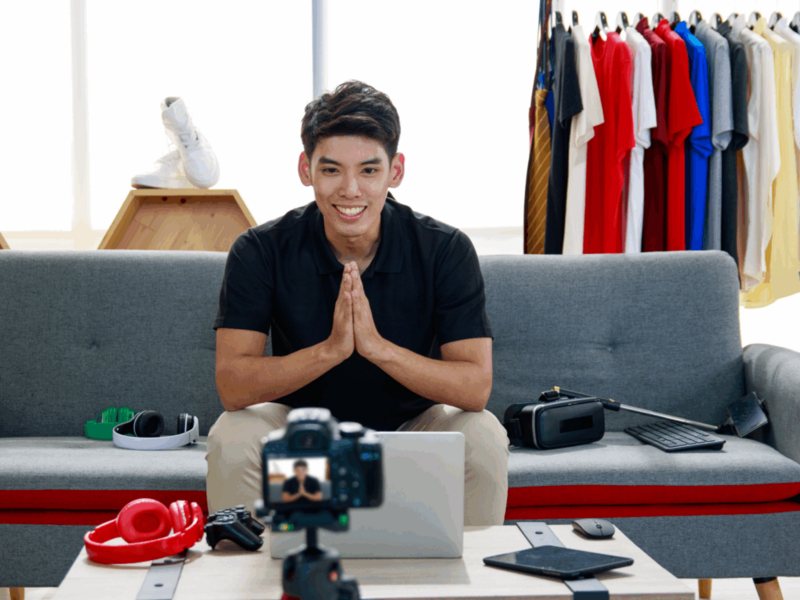 A young man is filming himself with different YouTube merch in the background.