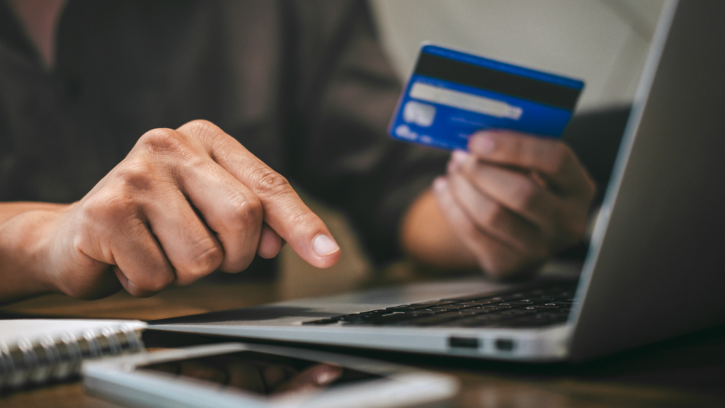 A person holding a credit card, making an online payment.