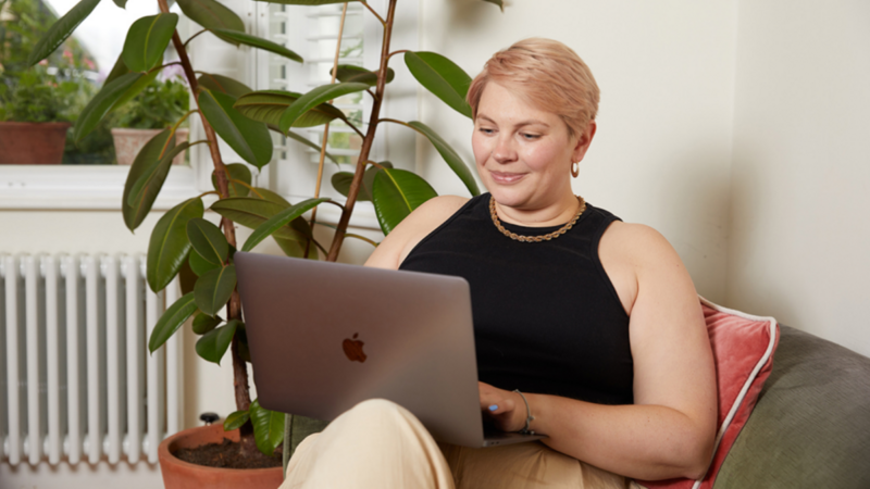 A woman sitting on a couch with a laptop on her lap.