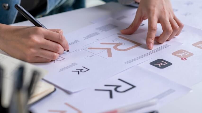 Woman's hands holding a pen and reviewing branding assets.