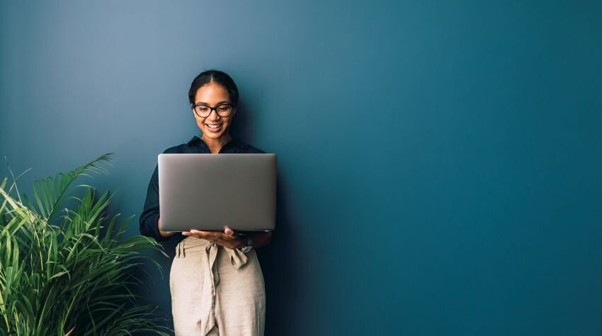 Woman standing with a laptop in her hands, working on product niche research.