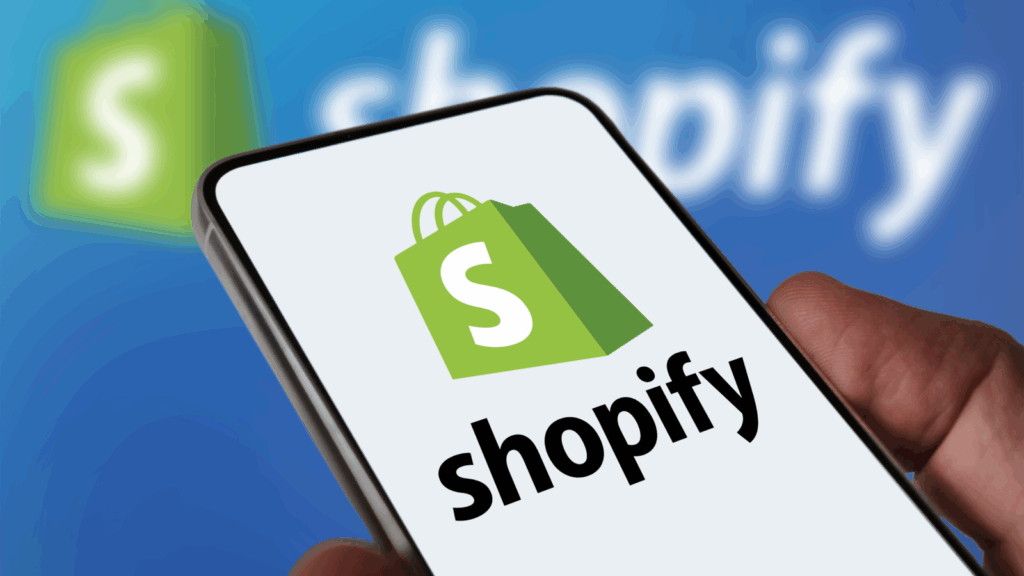 A person holding a phone with a Shopify logo on it.