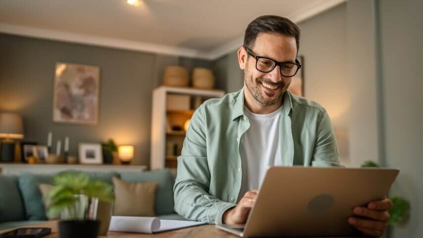 A man smiling while working on a laptop.