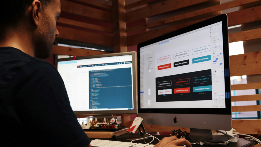 A man sitting in front of a monitor and setting up a Shopify store.