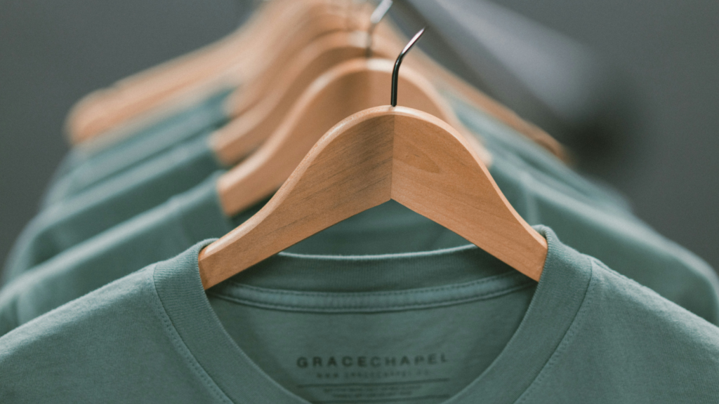 A row of green t-shirts neatly hanging on hangers, showcasing their vibrant color and casual style.