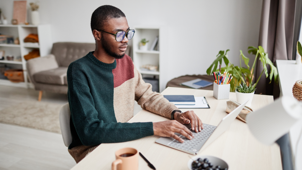 A man sitting at a table and working on a laptop.