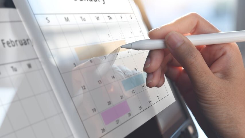 A person designing a digital planner on a tablet while using a touch screen stylus.