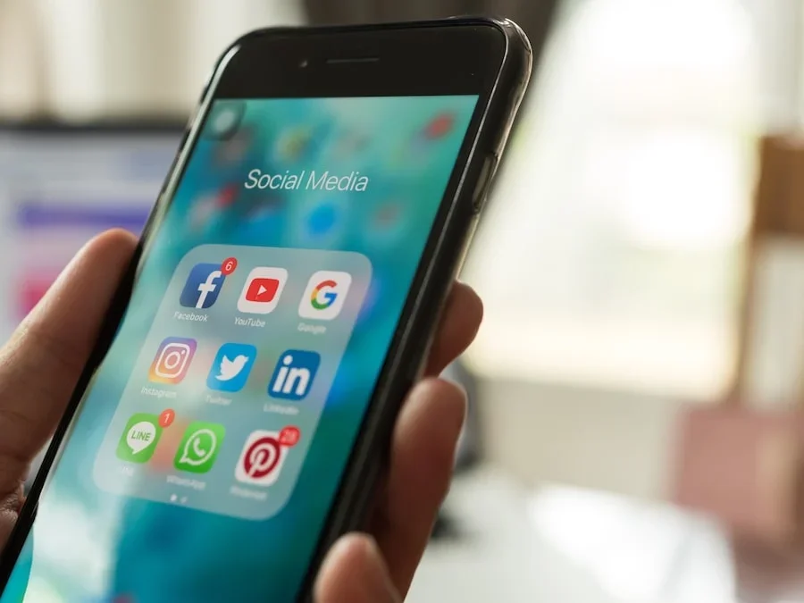 A person holding phone with social media applications on the screen.