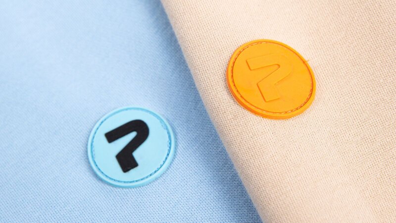Two circular patches: one blue, one orange, with Printify’s logo inside.