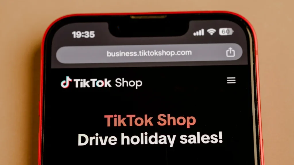 Close-up of a smartphone screen displaying the TikTok Shop webpage, titled "Drive holiday sales!" The tone is inviting and promotional.