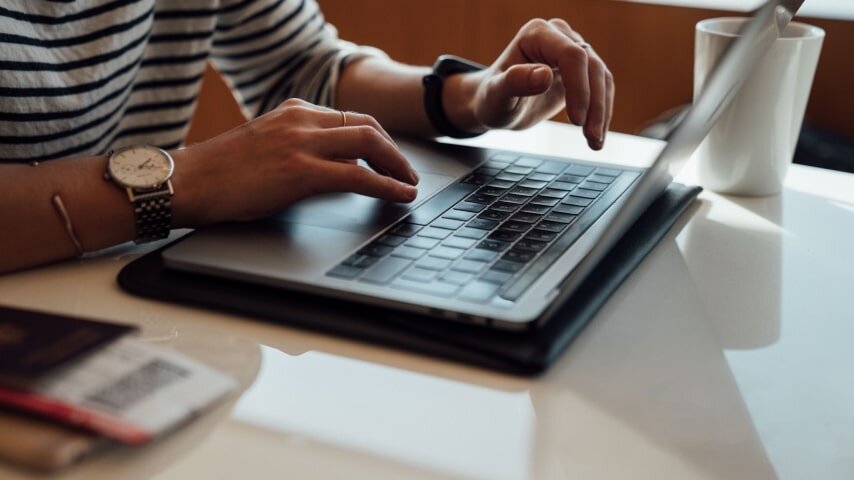 A human sitting next to the laptop writing.