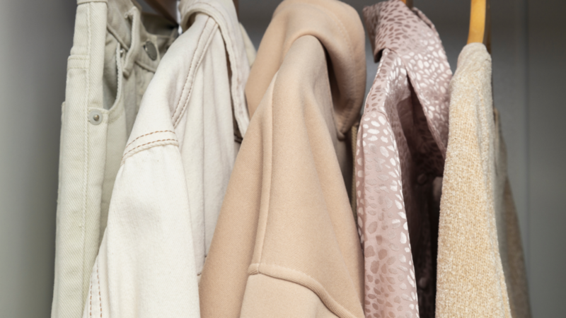 A closet featuring a rack with various clothes neatly hanging, showcasing a range of colors and styles.