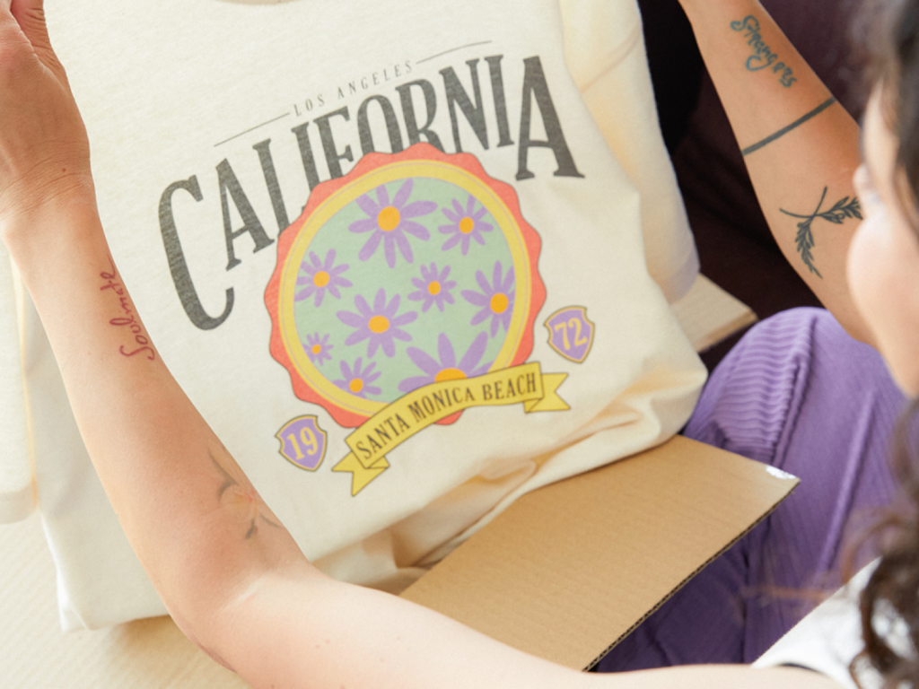 A woman holding a custom t-shirt made with print-on-demand as an example of how to make money as an influencer.