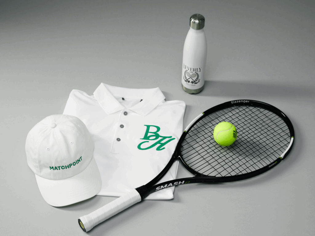 A hat, polo shirt, water bottle and tennis racket on a grey background as an example of swag bag ideas.
