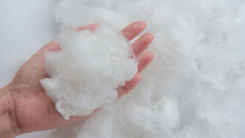 Person holding a handful of white polyester fiber.