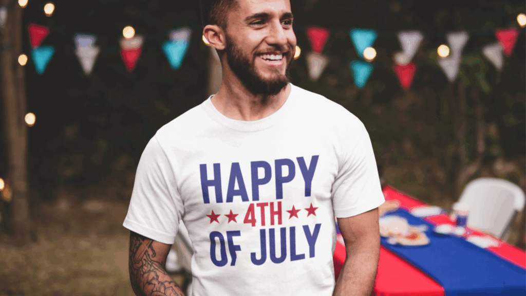 A smiling man wearing a “Happy 4th of July” t-shirt.