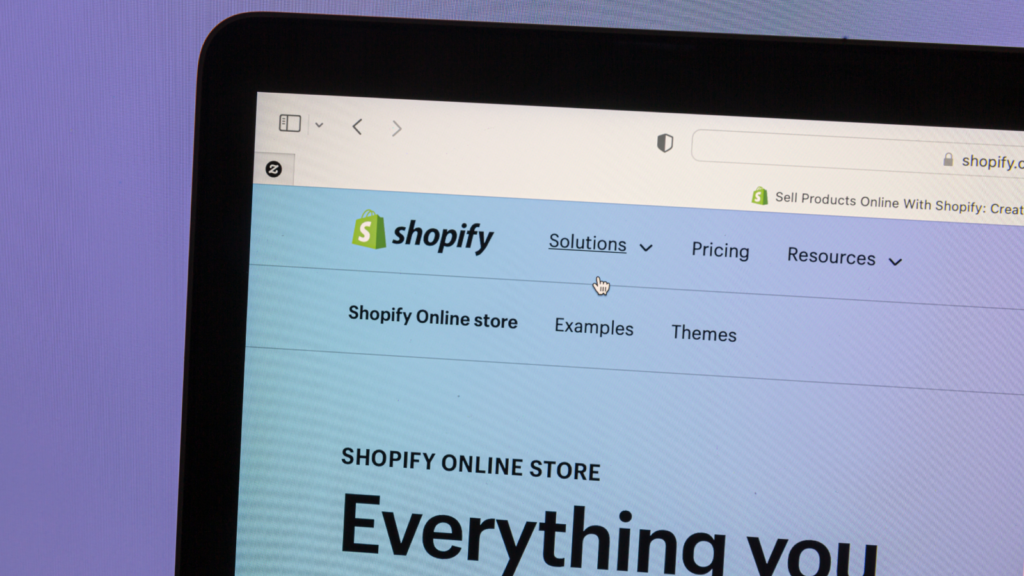 A corner of a laptop screen with Shopify’s homepage open.