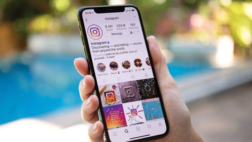 A man holding a mobile phone with Instagram open.