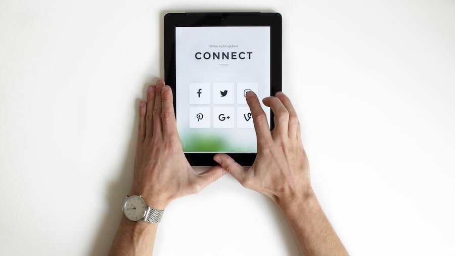 A person holding a tablet with social media icons on.