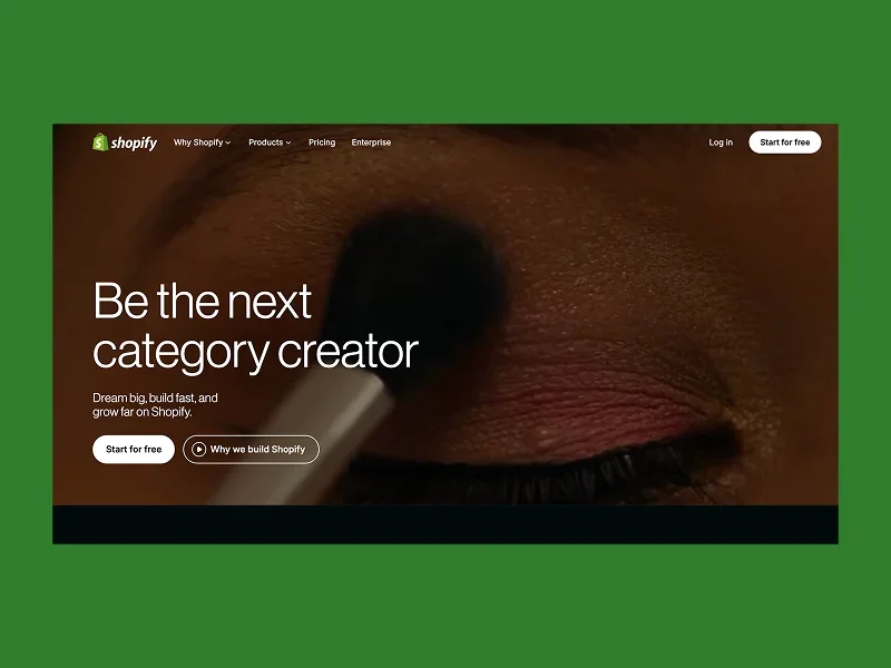 Close-up of an eye being delicately brushed with makeup, overlaid text reads "Be the next category creator" on Shopify's promotional webpage.