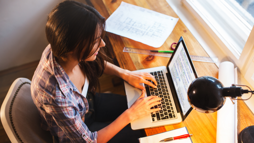 A woman types on her laptop at a desk, focused and engaged in her work.