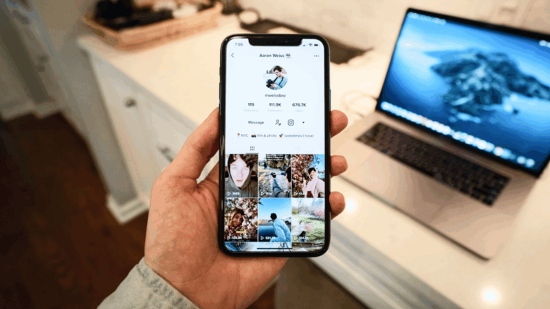 A man holding a mobile phone in his hand with the TikTok app open.
