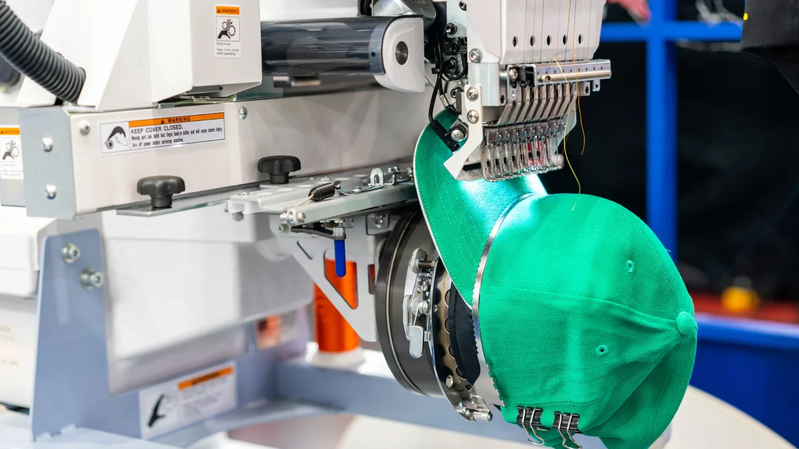 A green hat being embroidered with a logo.