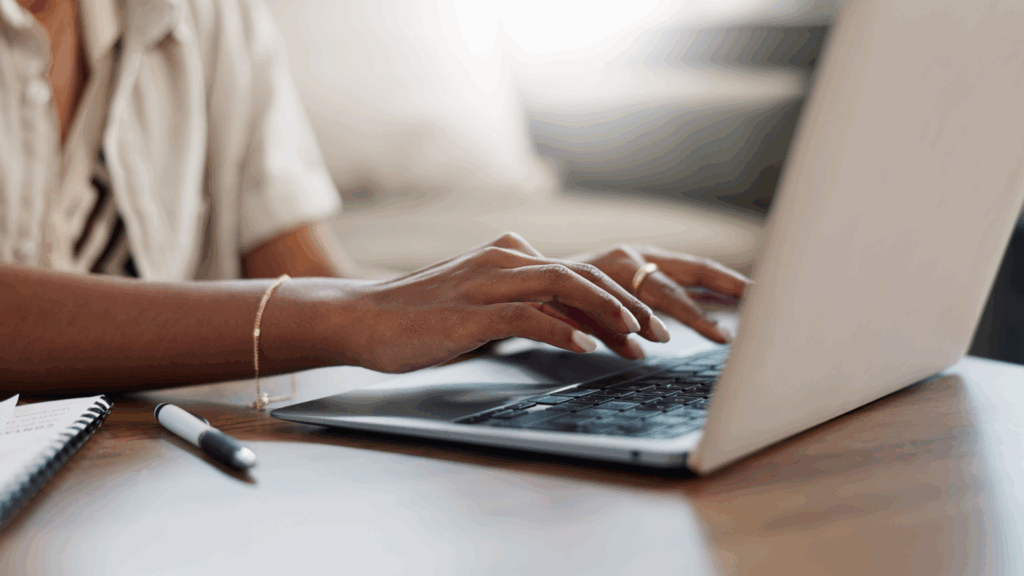A woman is typing on a laptop.