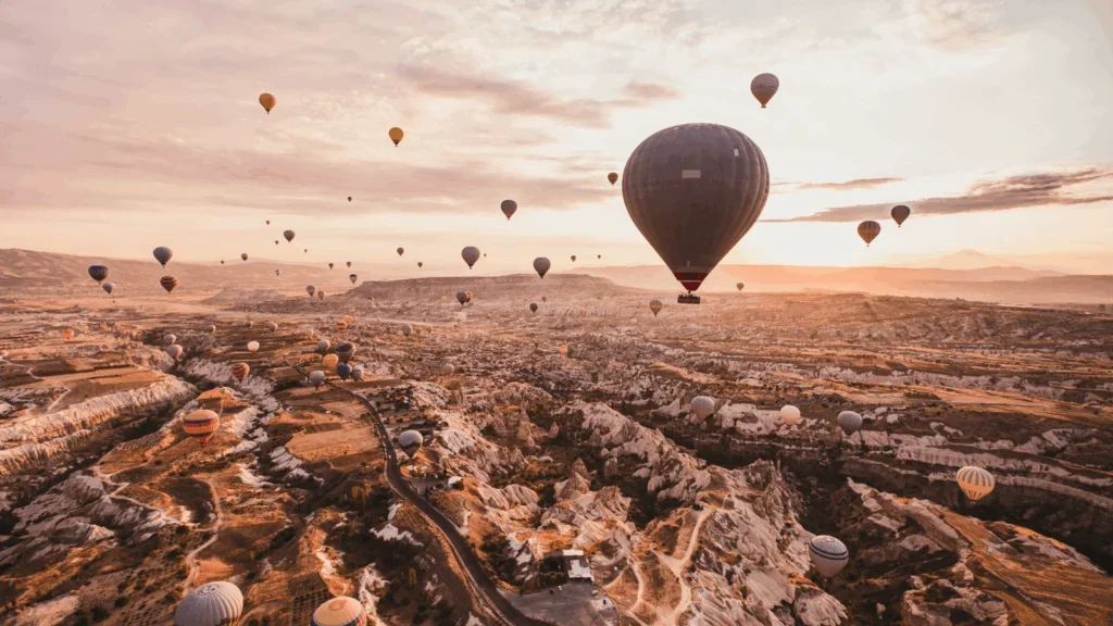 A colorful array of hot air balloons floats gracefully over a lush valley under a clear blue sky.