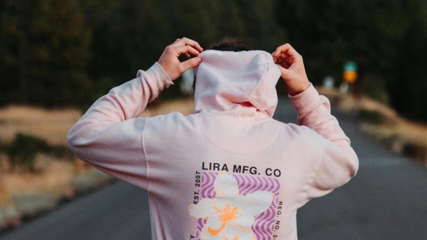 A man wearing a custom pink hoodie with a back print.