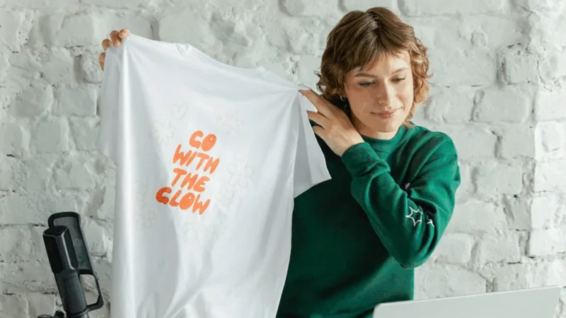 A woman showing a custom made t-shirt to the camera.