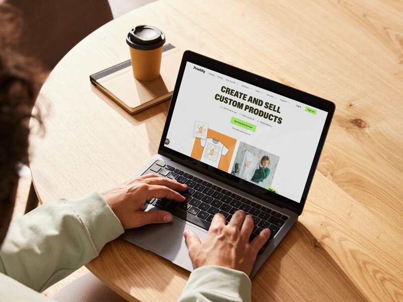 A person using a laptop with Printify’s homepage on the screen.