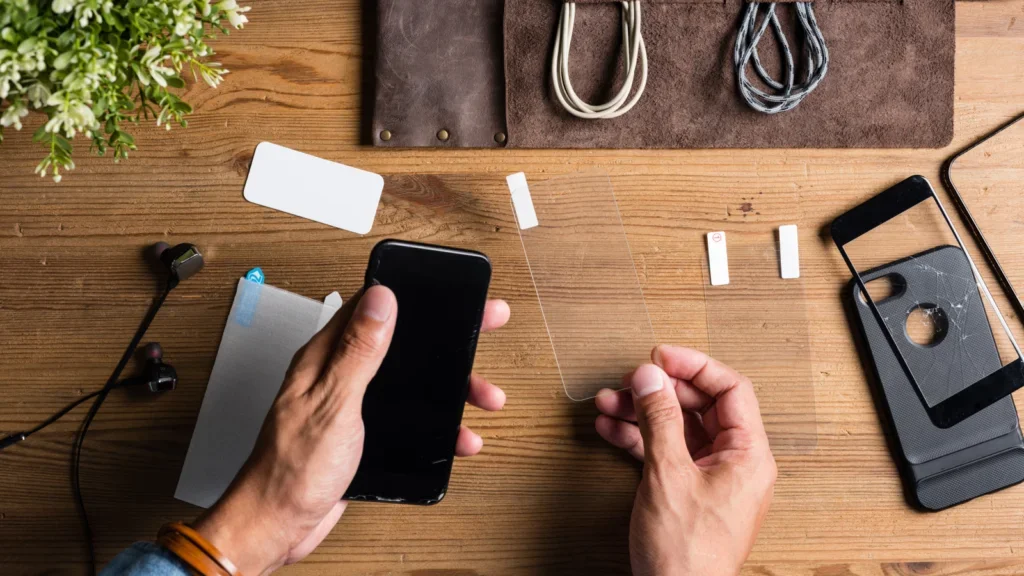 A person sitting at a table, focused on using a cell phone in their hands.