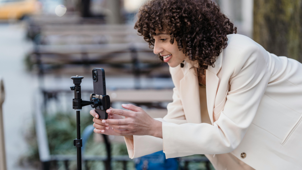 A woman setting up a mobile phone on a tripod.