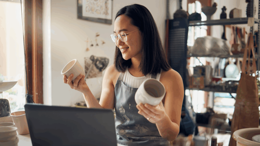 A woman is holding two mugs.