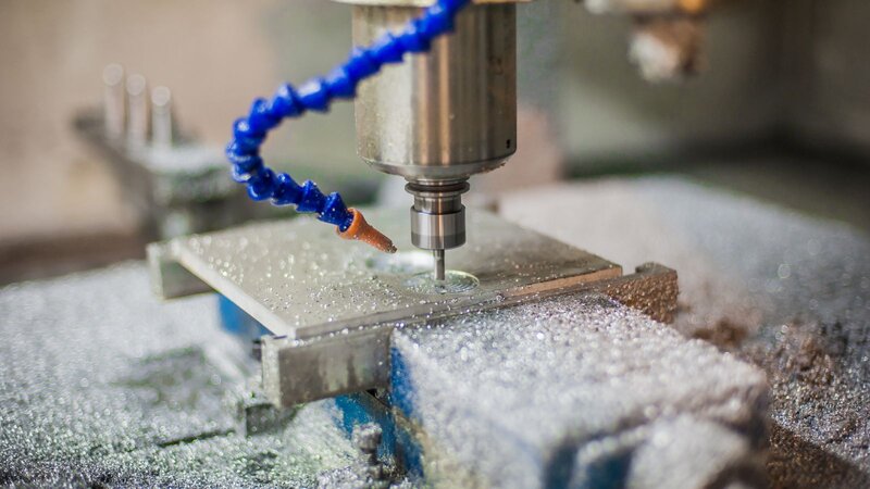 A person carefully uses a pen to shape a gold ring on a work surface, showcasing craftsmanship and attention to detail.