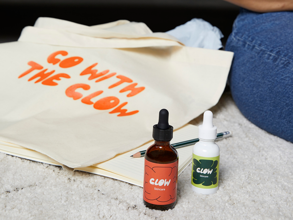 Custom “Go with the glow” tote bag with personalized “Glow” skincare products on a rug.
