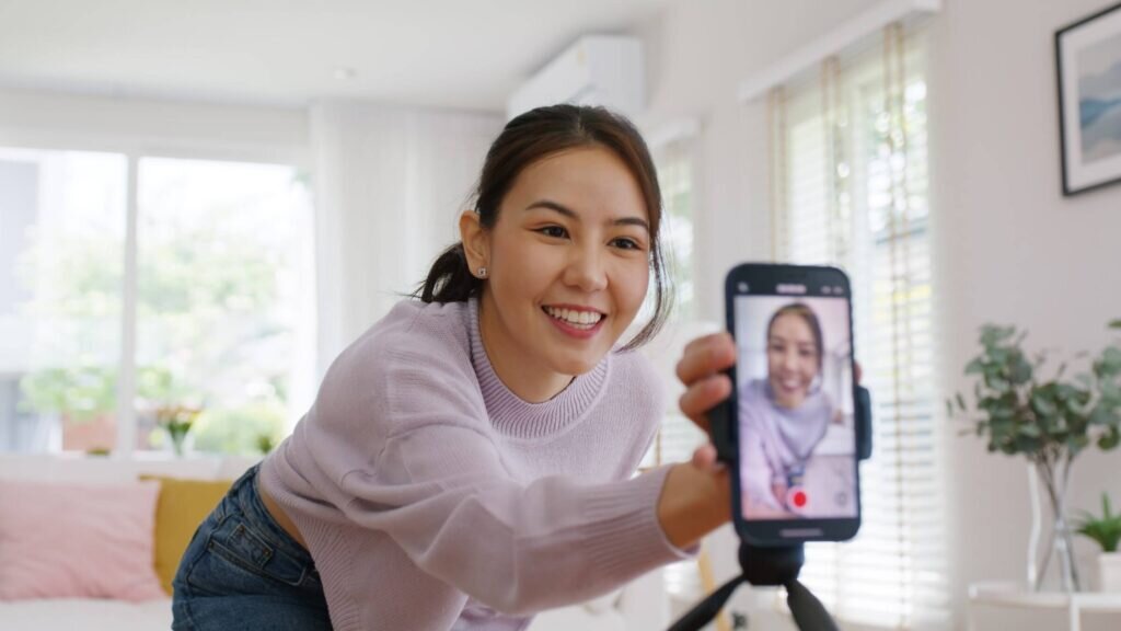 A woman filming herself with her phone for a TikTok video, smiling and enjoying the moment.