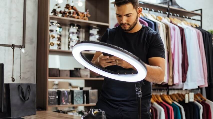 A man using social media apps on his phone to promote his clothing line.