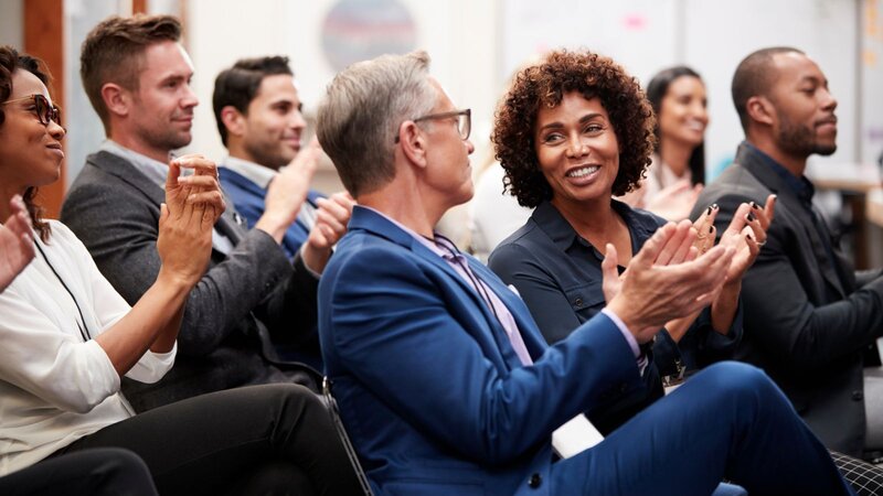 A smiling audience applauds during a business seminar.