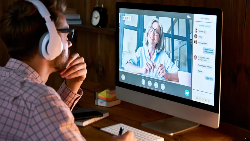 A man with headphones is on the online video call, doing an online coaching session.