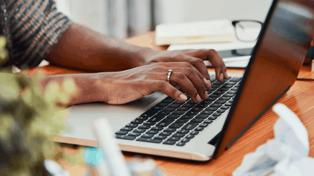 A person typing on a laptop keyboard.