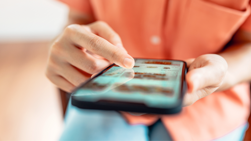 A person using a smartphone, scrolling through content on the screen.