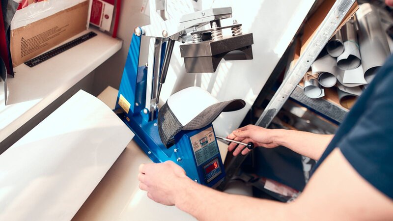 A person printing a print on a hat