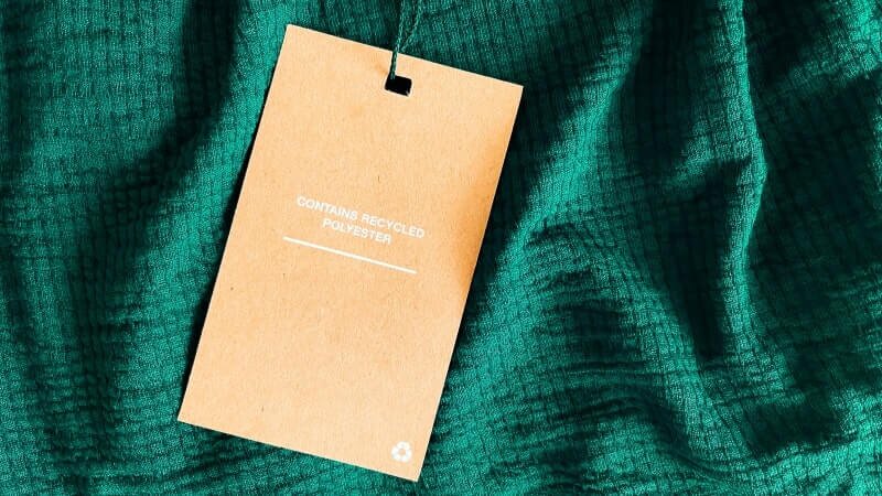A green garment with a label saying “Contains recycled polyester.”