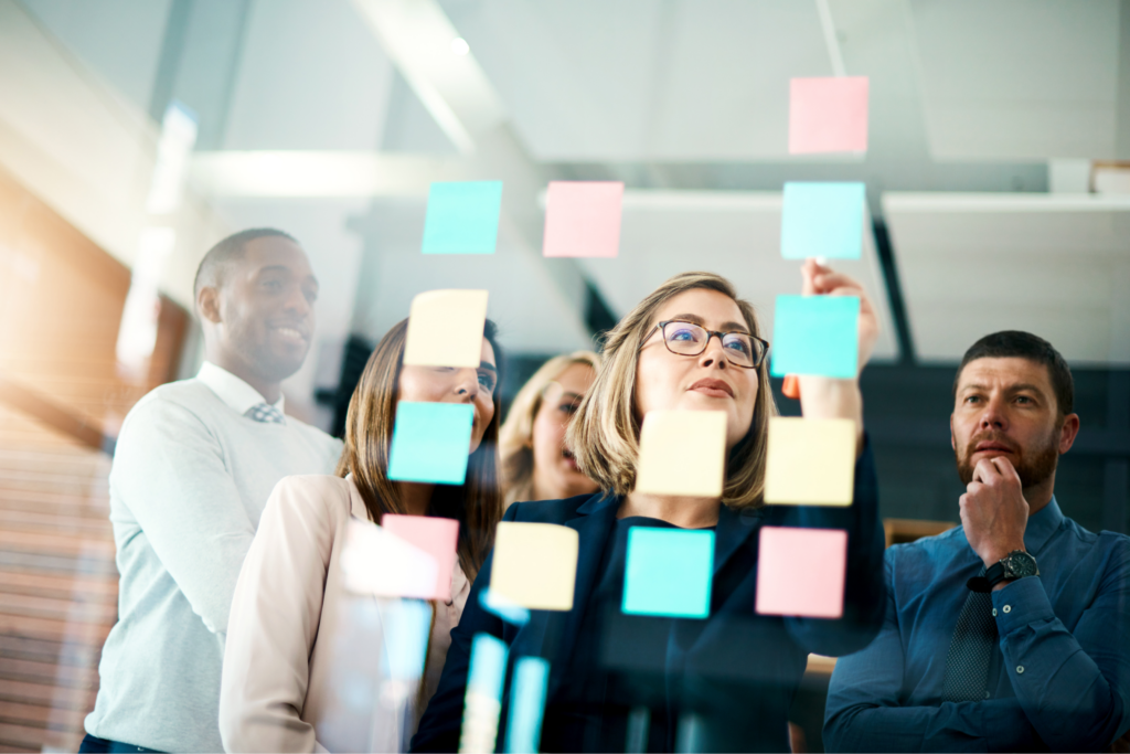 A group of people putting sticker notes on glass as a process of making a decision.